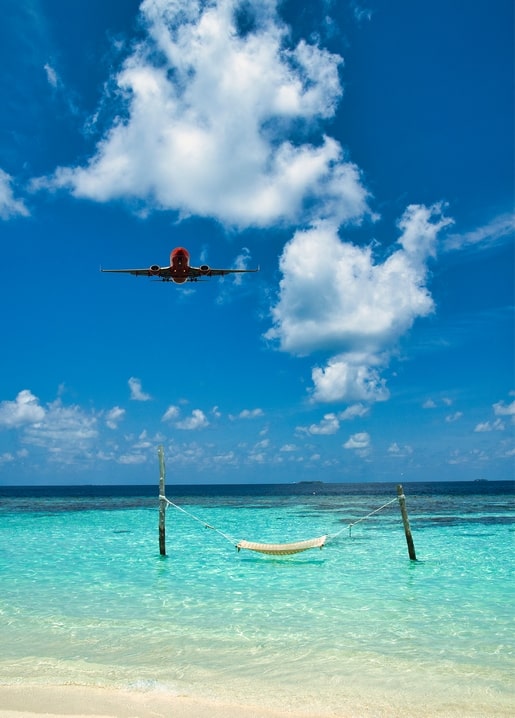 Airplane flying over a hammock in turquoise sea water near the beach