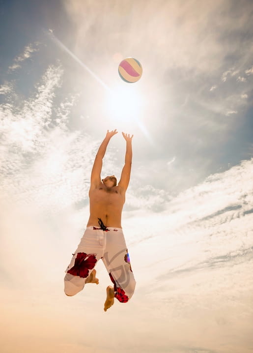 Mann springt zum Beachvolleyball-Schlag vor strahlend sonnigem Himmel