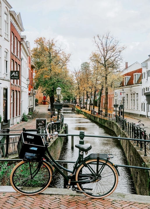 Fahrrad am Kanalgeländer in einer europäischen Altstadt mit Herbstbäumen