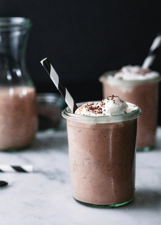 Glas Schokoladen-Milchshake mit Sahnehaube und Kakaosplittern auf Marmor