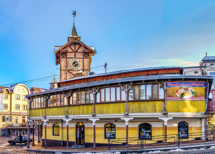 Yellow wooden market building with a clock tower under snow in Chortkiv, Ukraine