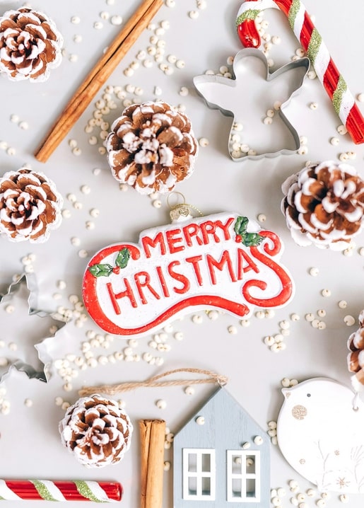 Hand-painted ‘Merry Christmas’ plaque among pinecones, cinnamon sticks and candy canes