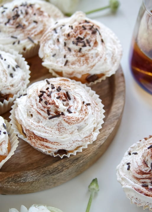 Zimt-Sahne-Cupcakes mit Schokoladenstreuseln auf einem Holzbrett