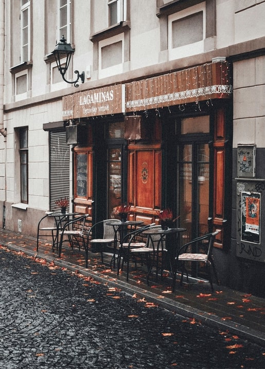 Kopfsteinpflaster-Café mit Tischen und Herbstlaub auf dem Gehweg