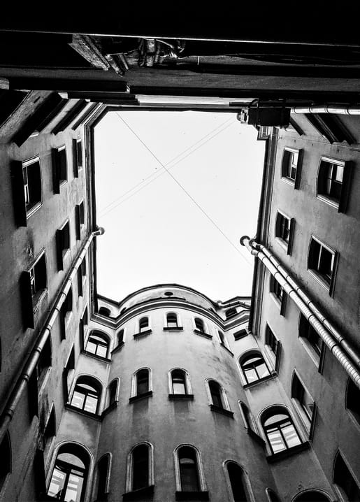 Blick senkrecht nach oben durch einen runden Hinterhof, Schwarzweißfoto