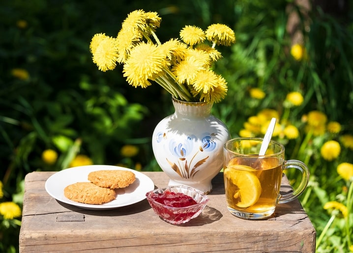 Dandelion bouquet, tea with lemon, oatmeal cookies, and jam on a garden crate