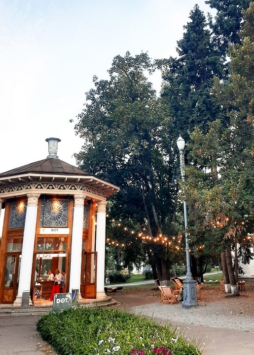 Hölzernes Rotunden-Café „DOT.“ unter Lichterketten in der Dämmerung auf dem VDNG
