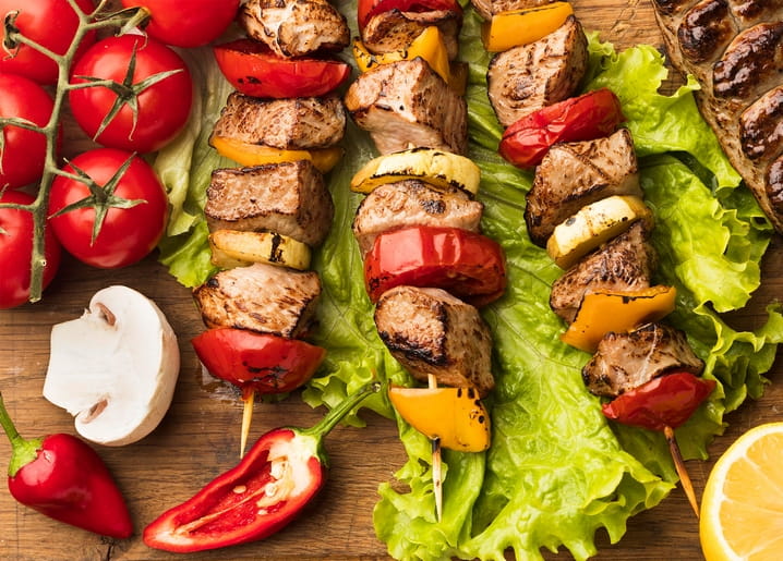 Grilled meat and vegetable skewers on lettuce with cherry tomatoes, mushroom, chili, and lemon