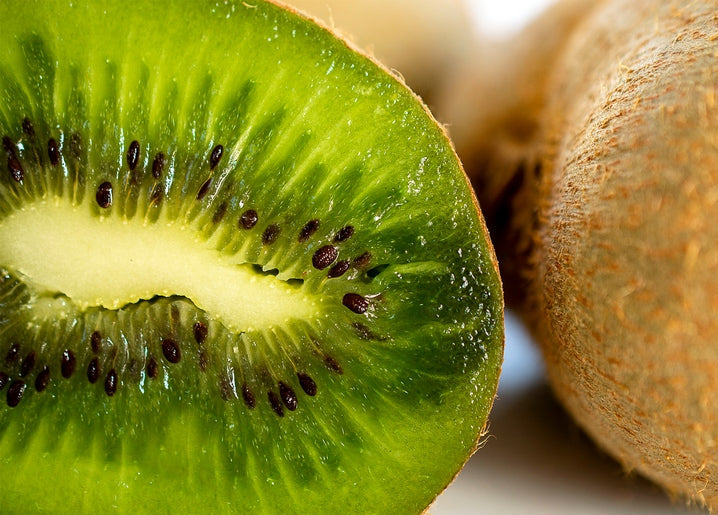 Macro shot of a halved kiwi showing green flesh and black seeds