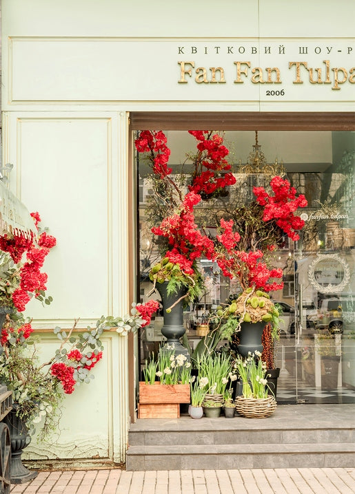 Flower shop entrance in Kyiv framed by deep red blossoms and baskets of white narcissus