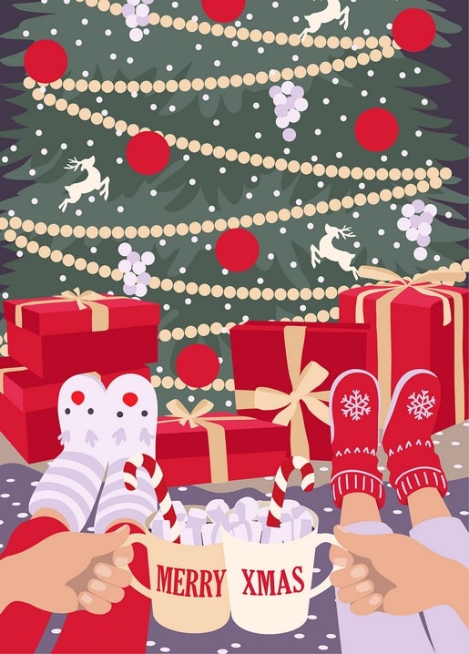 Zwei Hände halten Tassen mit der Aufschrift Merry Xmas, Marshmallows und Zuckerstangen vor einem Weihnachtsbaum