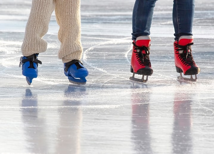 Close-up of red and blue ice skates gliding across a sunlit rink
