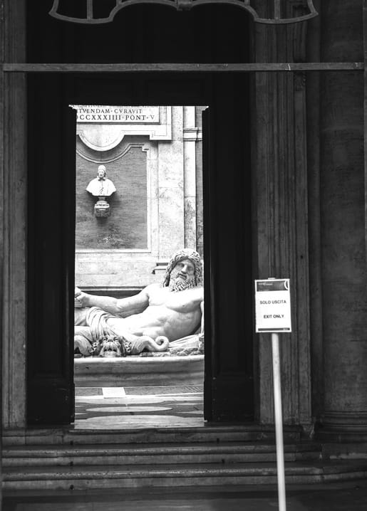 Schwarzweißfoto einer barocken Brunnenstatue durch eine römische Türöffnung