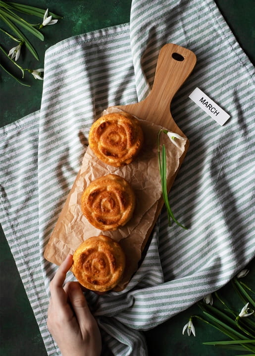 Rose-shaped pastries on a wooden board with snowdrops and a paper tag reading ‘March’