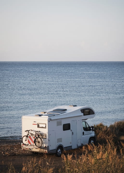 Wohnmobil am Meer bei Sonnenuntergang mit Fahrrädern am Heckträger