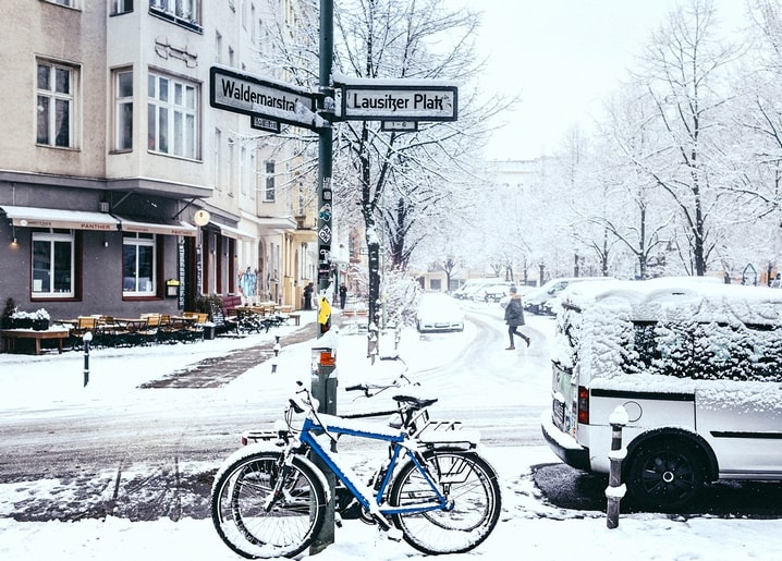 Snow-covered Berlin street at Lausitzer Platz with a bicycle and van