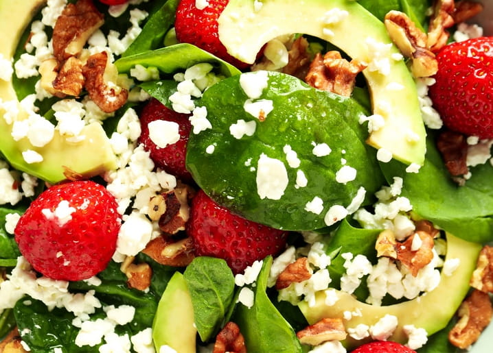 Close-up of spinach salad with strawberries, avocado, feta and walnuts