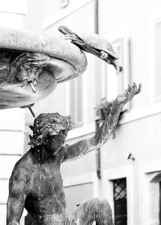 Verwitterte Steinstatue greift nach einer Schildkröte am Brunnenrand, Schwarzweißfoto