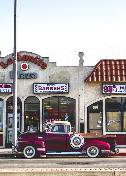 Bordeauxroter Oldtimer-Pickup vor Retro-Friseursalon mit rotem Ziegeldach