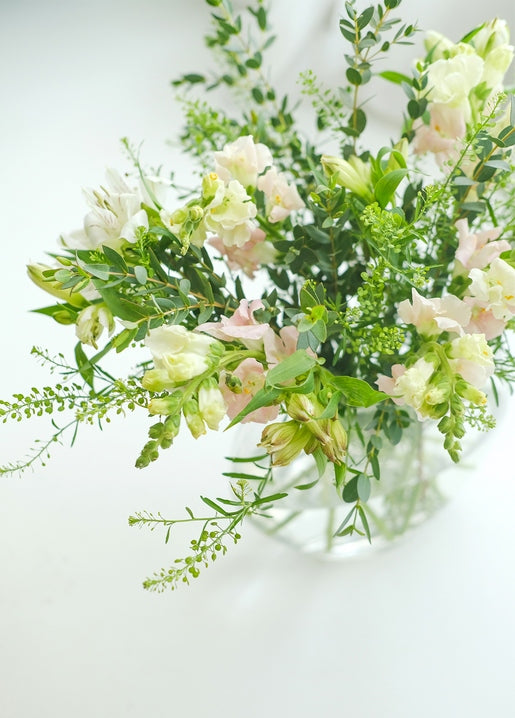 White and blush bouquet with eucalyptus greenery in a clear glass vase