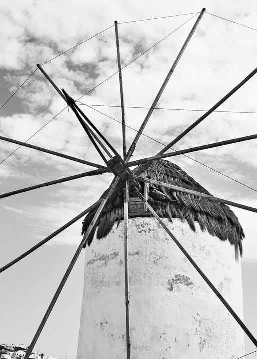 Weiß getünchte Windmühle mit Strohkappe und Holzflügeln vor bewölktem Himmel, Schwarzweißfoto