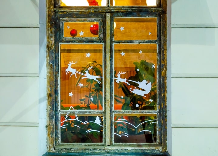 Old wooden window glowing at night with Santa's sleigh and reindeer decals