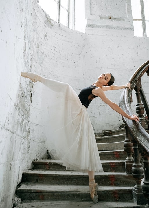 Ballerina auf Spitze in Arabeske auf einer verwitterten Steintreppe