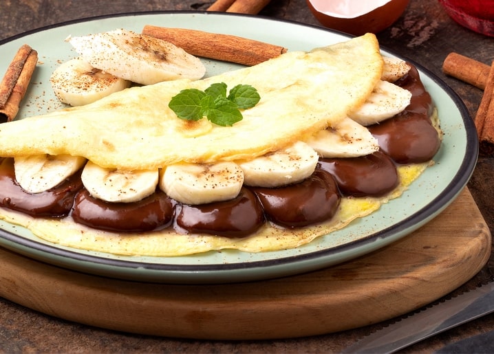 Млинець, згорнутий з бананом і шоколадним соусом
