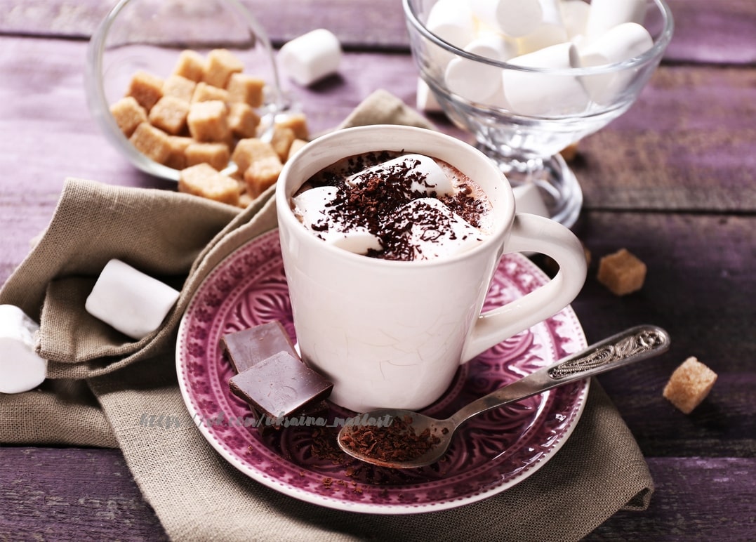 Weiße Tasse heißer Schokolade mit Marshmallows und geriebener Schokolade auf Blumenuntertasse
