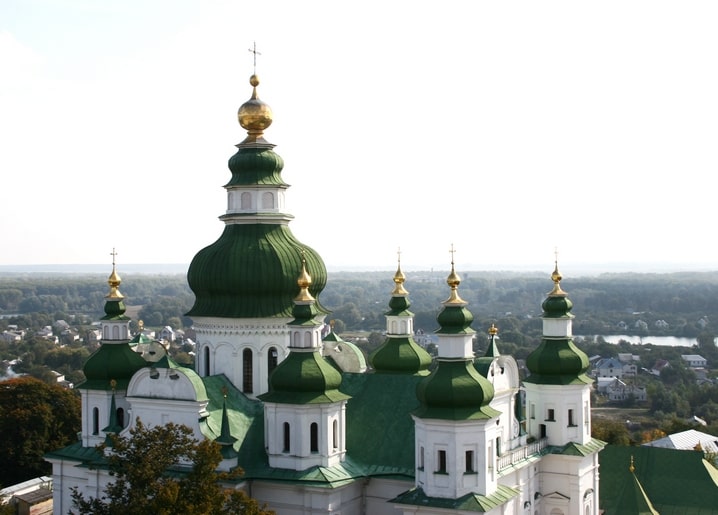 Вид з висоти на зелені бані собору над дахами та річкою Чернігова