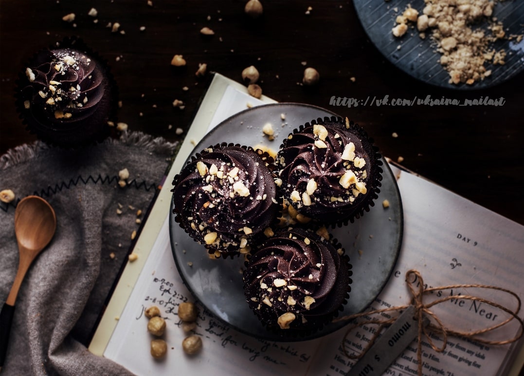 Schokoladen-Cupcakes mit gehackten Haselnüssen auf einem aufgeschlagenen Tagebuch