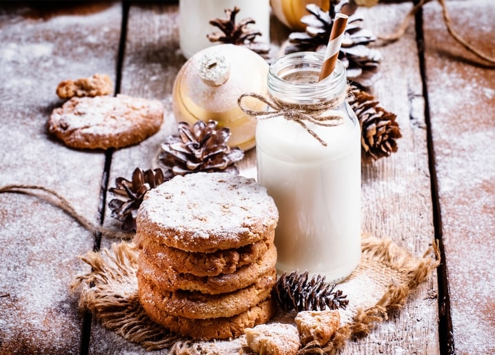 Stapel Weihnachtsplätzchen neben einer Milchflasche mit Strohhalm und Zapfen