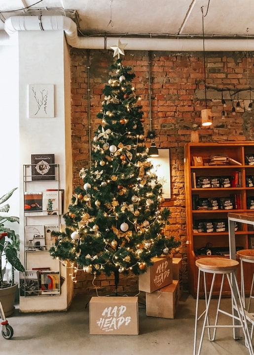 Decorated Christmas tree with gold baubles and lights in a loft bookstore corner