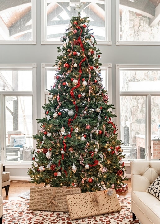 Geschmückter Weihnachtsbaum mit roten und silbernen Kugeln und Geschenken darunter