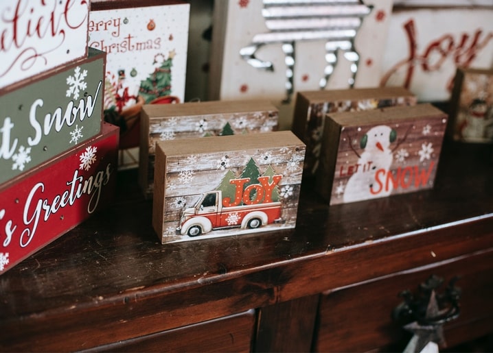 Holzblock mit Lastwagen und Schneemann zwischen weihnachtlichen Schildern auf Holzregal