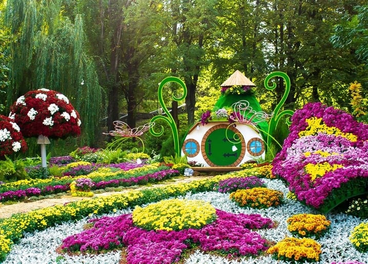 Hobbit-style garden house surrounded by magenta and yellow chrysanthemums at a Kyiv flower show