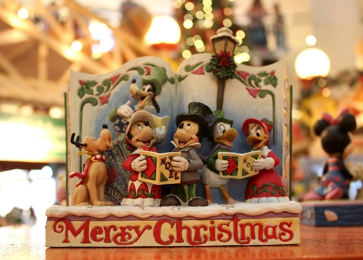 Disney-Buchfigur mit Mickey, Goofy, Donald, Daisy und Pluto beim Singen unter einer Laterne.