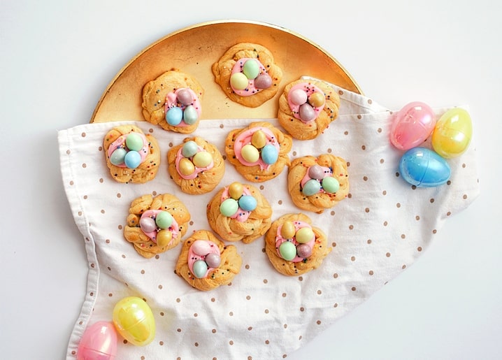 Braided nest cookies with pastel candy eggs on a gold plate among Easter eggs