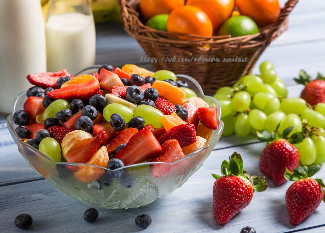 Glass bowl of fruit salad with strawberries, blueberries, grapes and mandarin