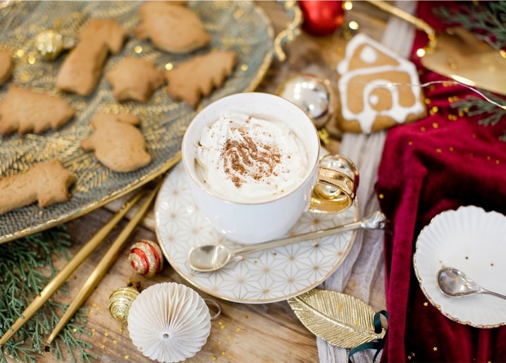 Cappuccino mit Sahne und Zimt neben Lebkuchen und einem kleinen Lebkuchenhaus