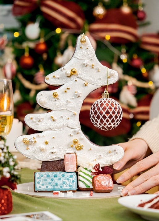 Lebkuchen-Weihnachtsbaum mit Perlen und goldenen Kugeln auf einem festlich gedeckten Tisch