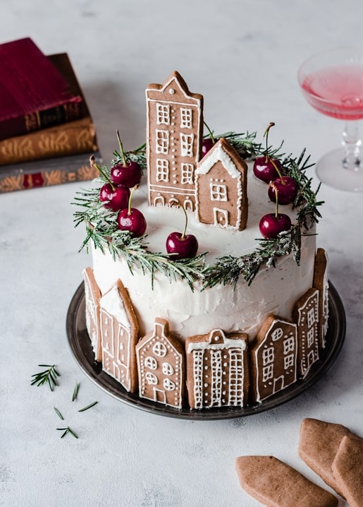 Torte mit Lebkuchenhäusern, Kirschen und einem Tannenkranz verziert
