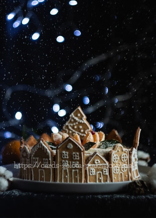 Kranz aus verzierten Lebkuchenhäusern auf einem Dessert mit Lichterketten und Schnee