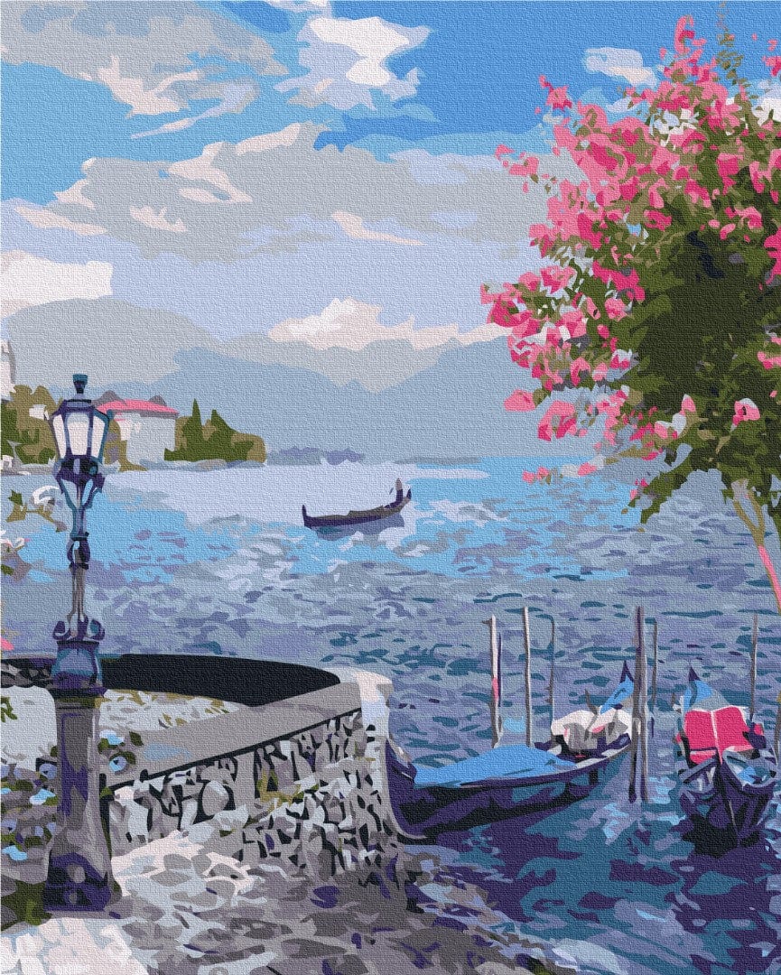 Gondolas moored on a calm lagoon beneath blooming pink bougainvillea and a wrought-iron lamppost