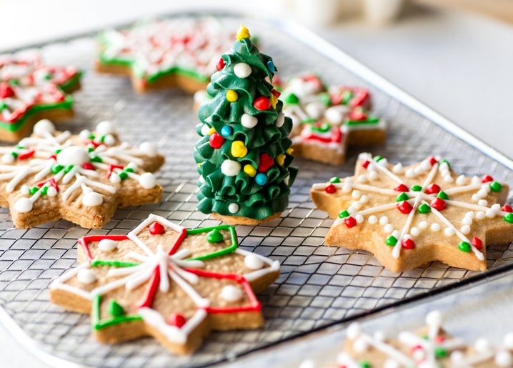 Iced star-shaped Christmas cookies with a 3D icing Christmas tree on a cooling rack