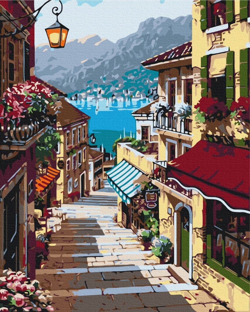 Italian coastal street lined with flowers and café awnings above a turquoise bay