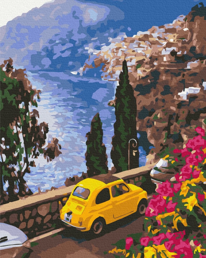 Yellow vintage car on a cliffside road above the sea, with cypress trees and bougainvillea in an Italian coastal village