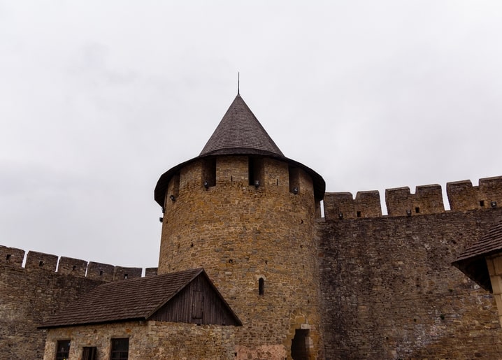 Кругла кам'яна вежа Хотинської фортеці з конічним дахом під хмарним небом