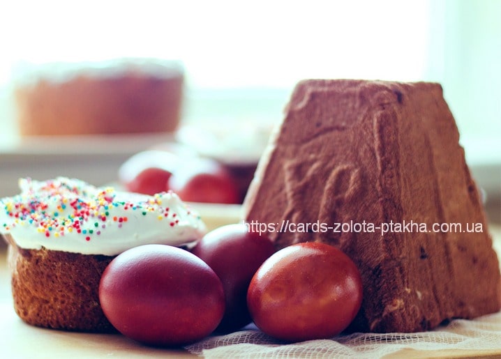 Easter kulich with sprinkles, red dyed eggs, and dark paska loaf on cheesecloth