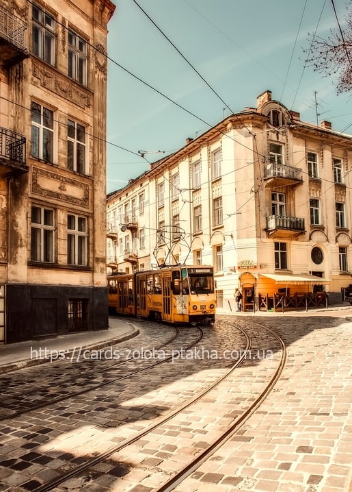 Yellow tram turning on a cobblestone street in Lviv's historic old town